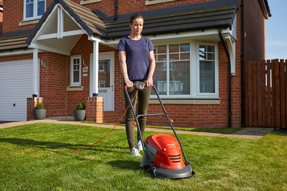 A woman mowing a lawn with a Flymo® SimpliStore 300 Li cordless lawnmower.